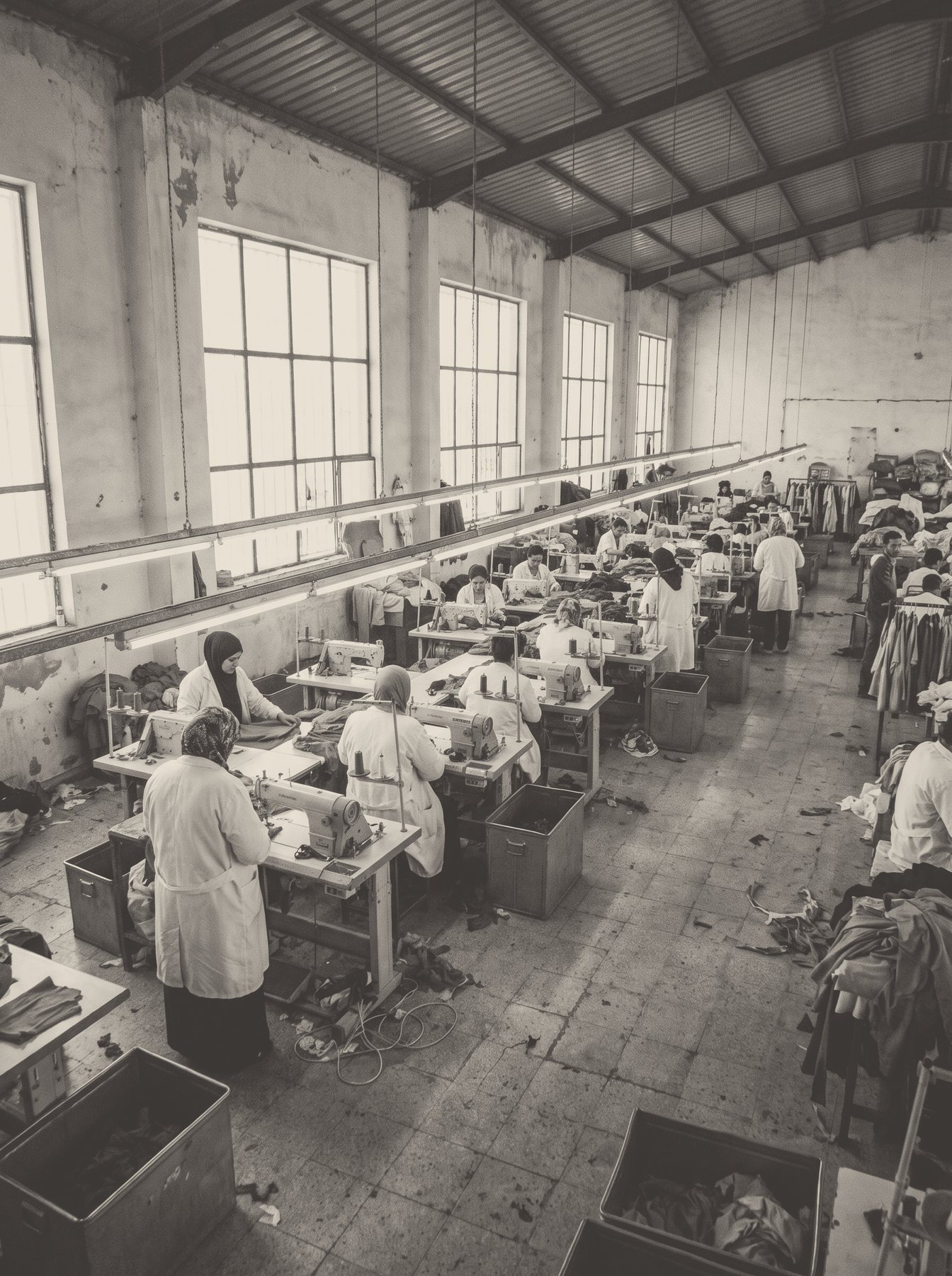 A row of operators at their sewing machines by the windows.